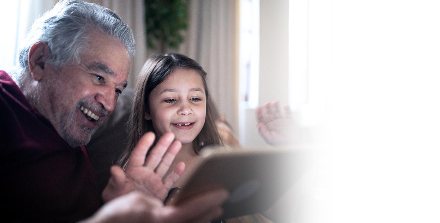 孩子和祖父坐在一起挥手，通过平板电脑上的视频会议保持联系